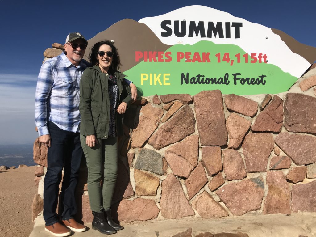 Standing by Summit sign at 14,115 ft. Pikes Peak Colorado in the Fall