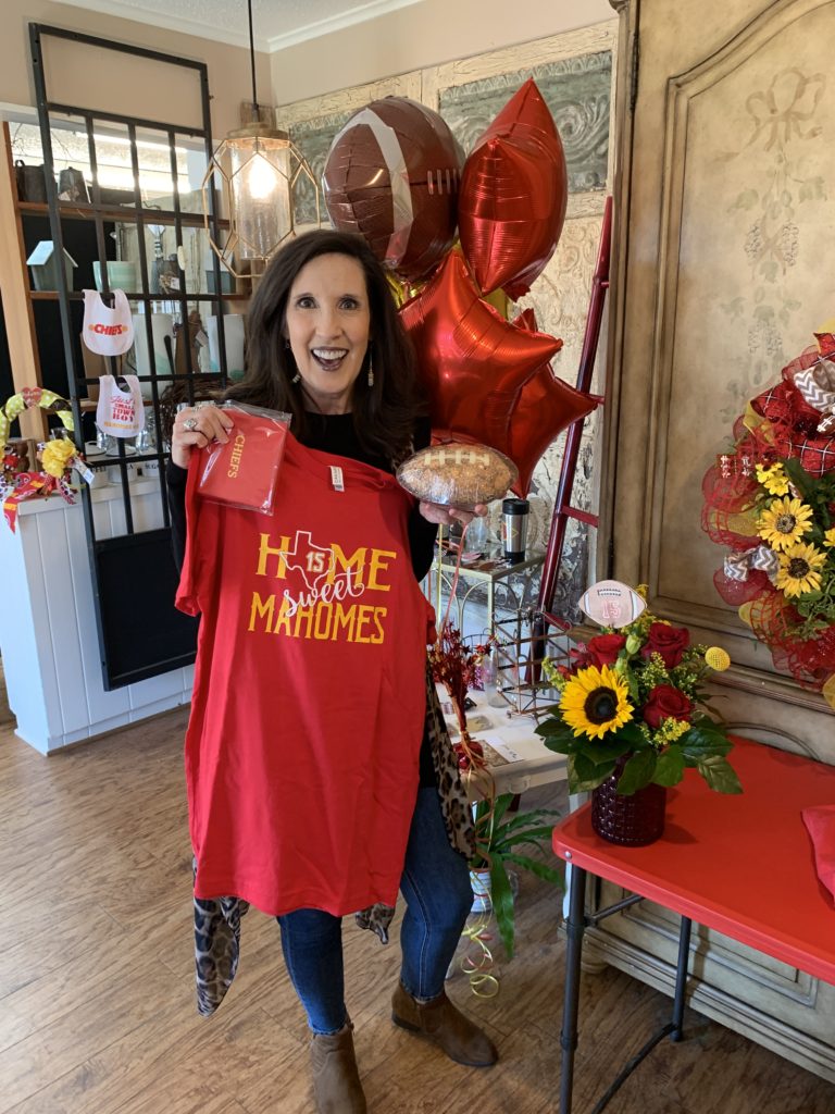 Holding up Home sweet Mahomes shirt at hometown flower shop, Whitehouse Flowers