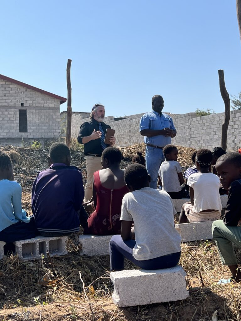 Preaching to congregation sitting on cinder blocks Zambia